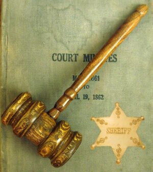 A gavel sheriff's start laid on top of a book titled "Court Minutes"