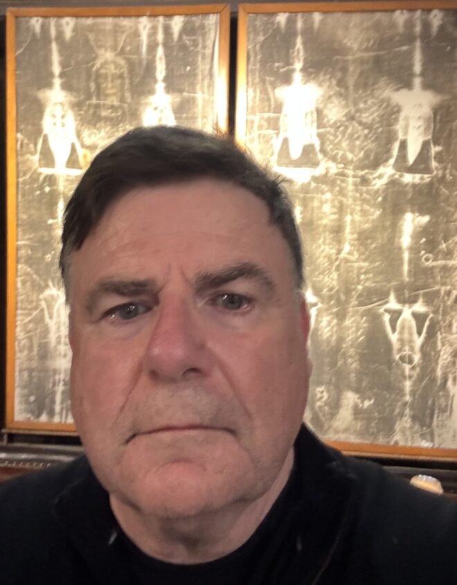 Bakchos standing in front of a copy of the Shroud of Turin at the Church of Saint-Sulpice.