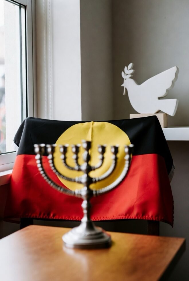 A menorah and an Indigenous flag with a peace dove above.