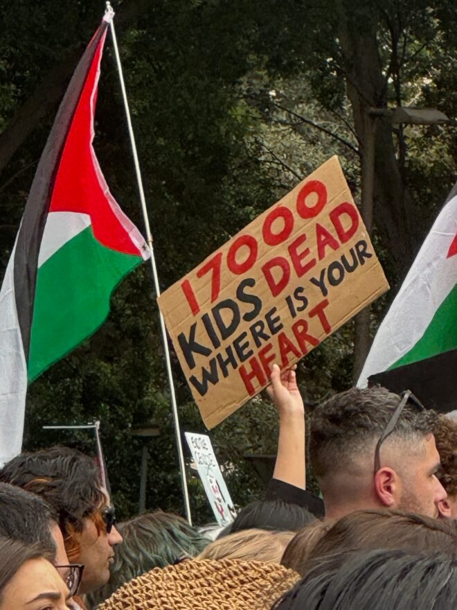 A Palestinian flag and a sign reading, "170,000, kids dead, where is your heart."