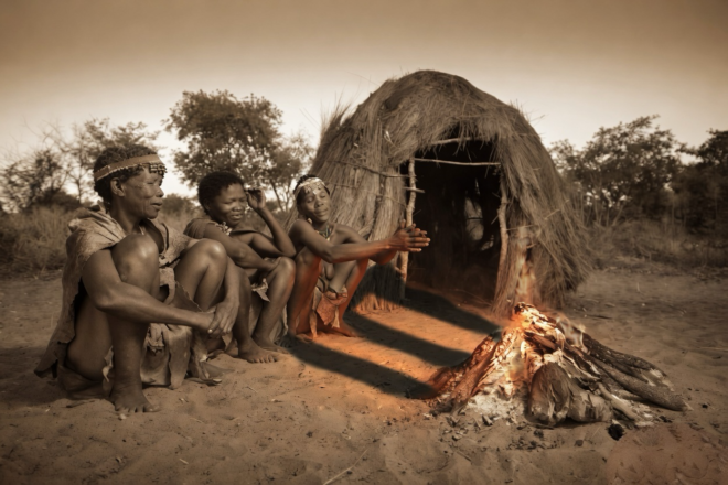 Indigenous peoplesitting by a hut.
